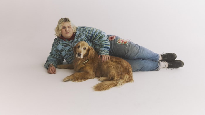 Une femme allongée avec son chien pose pour la photo. 