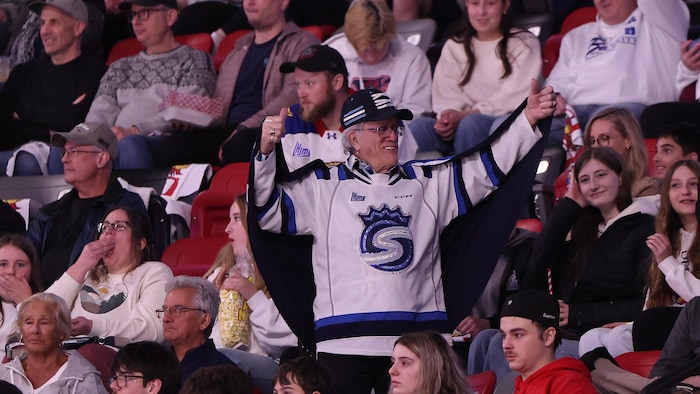 Un homme avec un chandail des Saguenéens debout dans les gradins à Moncton. 