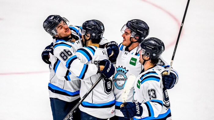 Des joueurs de hockey qui se félicitent après un but sur la patinoire. 