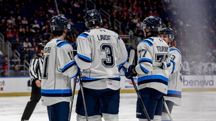 Des joueurs de hockey se parlent sur la glace.