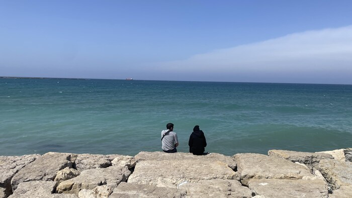 Deux hommes assis face à la mer.