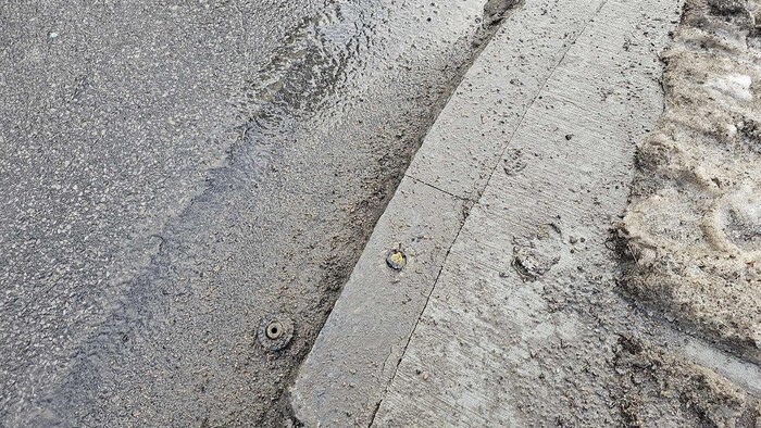 On the sidewalk, the base of a broken sign protrudes from the concrete. 