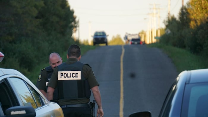 Des policiers en discussion près d'un véhicule de la Sûreté du Québec. 