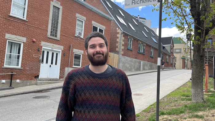 Un homme pose devant une rue.