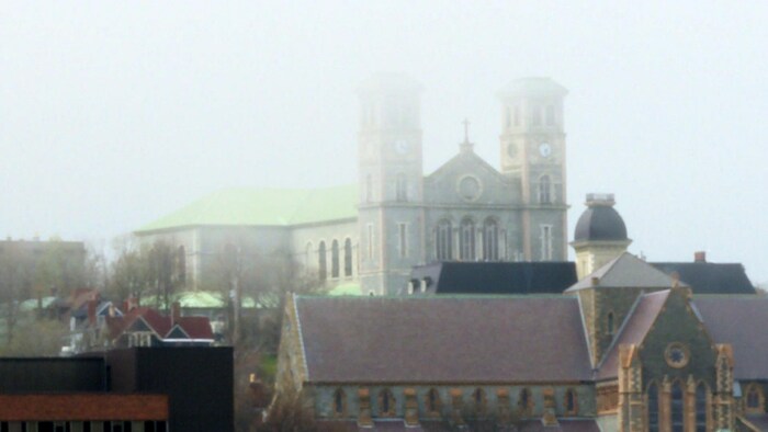 Les deux clochers d'une église disparaissent dans la brume.