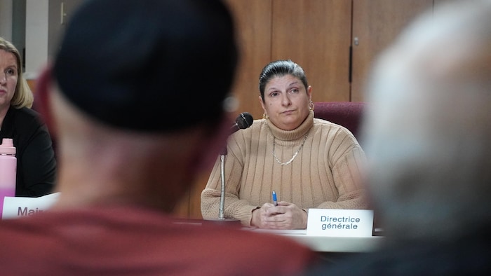 Marie-Josée Corbin devant la salle du conseil remplie de citoyens.