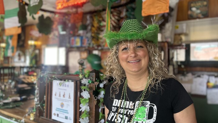 Une femme sourit à la caméra avec des accessoires verts.