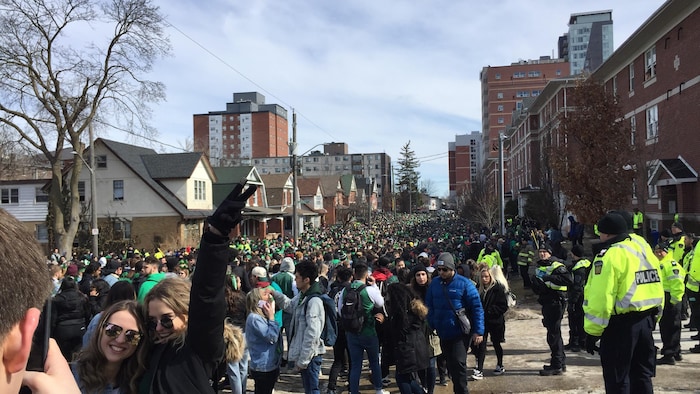 Des personnes célèbrent la Saint-Patrick sur la rue Ezra à Waterloo sous l’œil de policiers.