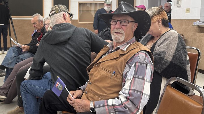 Un homme assis tient dans sa main un drapeau de l'Alberta.