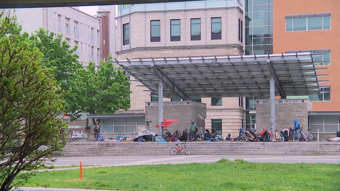 Un regroupement de personnes en situation d'itinérance sur une place publique.