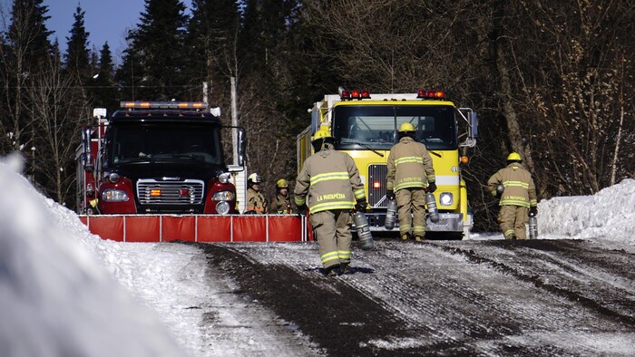 Des pompiers et deux camions de pompiers en hiver.