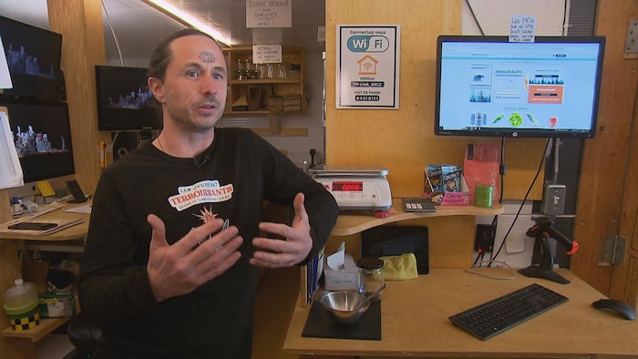 Conrad Goulet livre une entrevue, à côté de la caisse du comptoir.