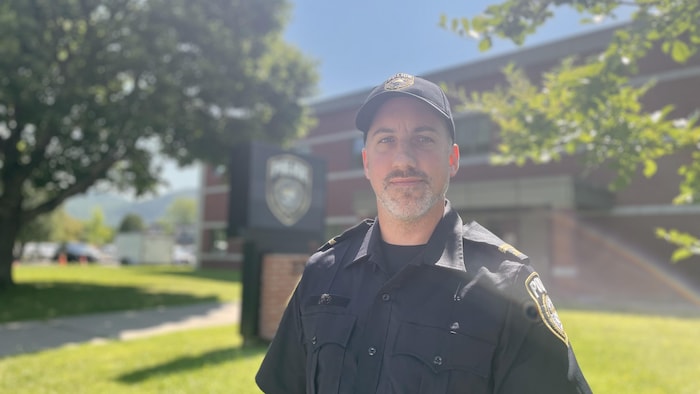 Portrait de Philippe Lapointe en uniforme, devant le poste de police.