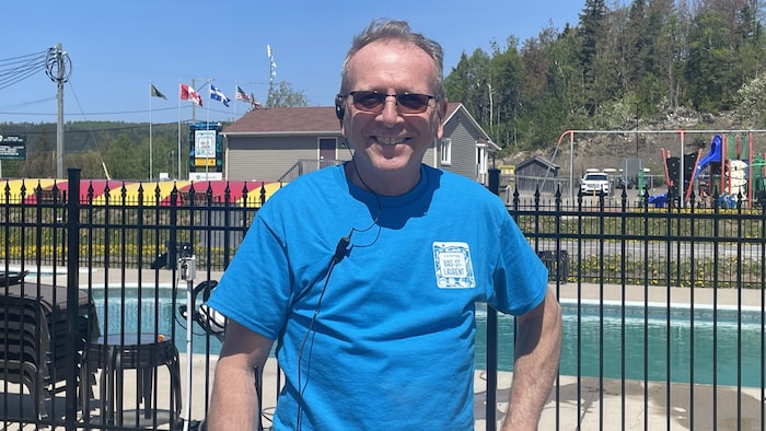 Un homme devant une grille et une piscine.