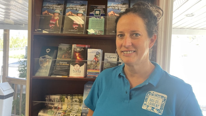 Une femme devant une étagère remplie de documentation touristique.