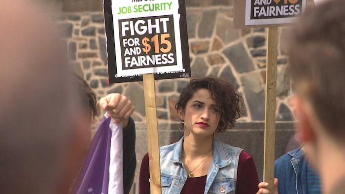 Una manifestante sostiene una pancarta pidiendo un salario mínimo de 15 dólares.