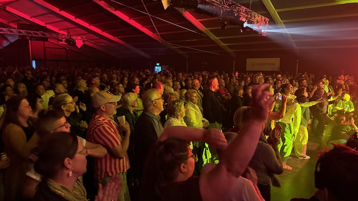 Une foule de personne dans le chapiteau du Festival en chanson s'anime face à une scène.