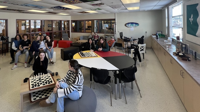 Des élèves font différentes activités dans une salle scolaire, dont jouer aux échecs.