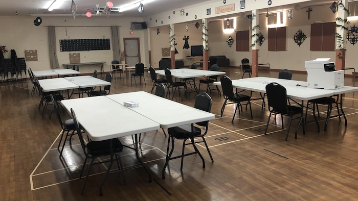 Une salle communautaire où on a mis des tables et des chaises à 2 mètres de distance.