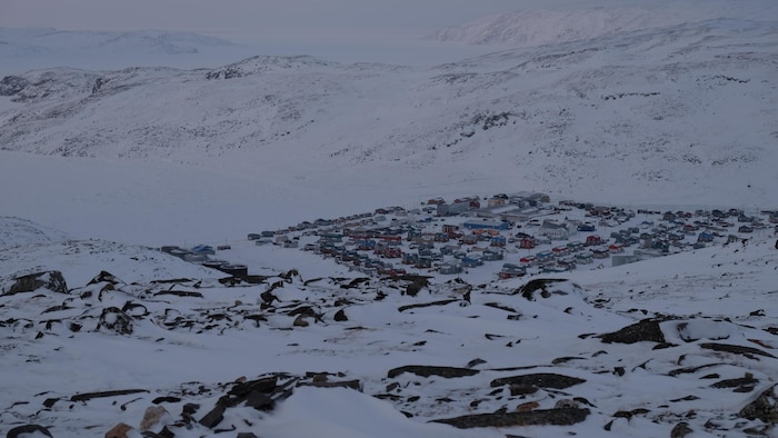 Vue plongeante sur un colony arctique, au bord d'une baie glacée.
