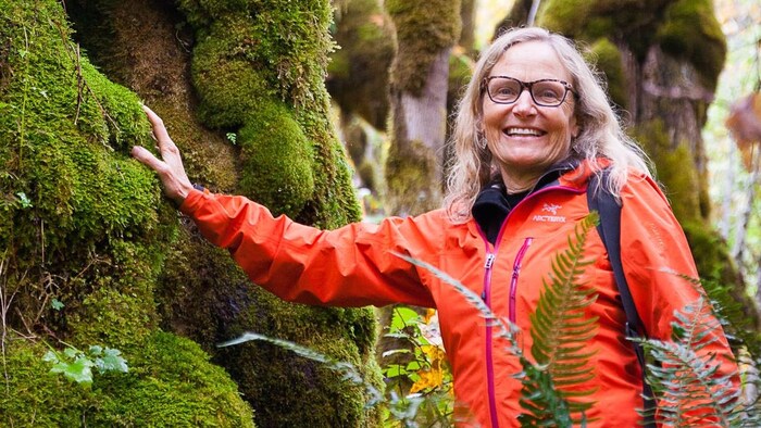 Sally Aitken, souriante, dans une forêt