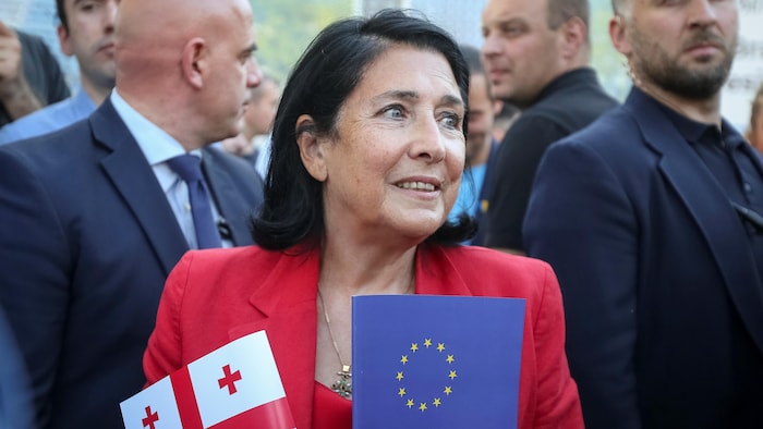 Salomé Zourabichvili, entourée de gardes, tient un drapeau de la Géorgie et un drapeau de l'UE.