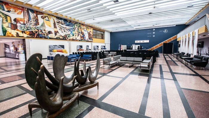 Salon d'aéroport avec sculpture et oeuvre d'art sur le mur.