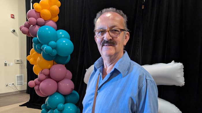 Un homme souriant devant des ballons.
