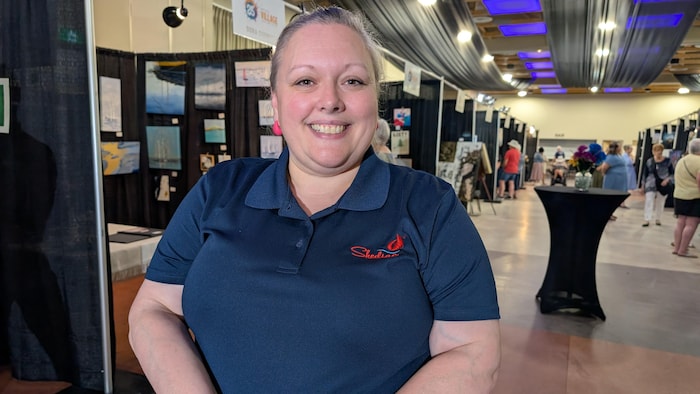 Une femme souriante dans un complexe avec plusieurs exposants.