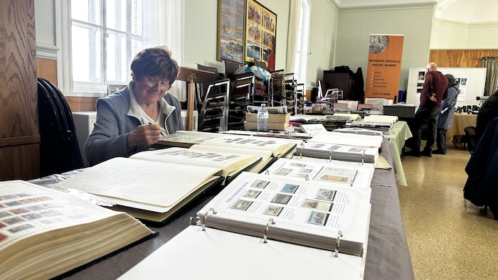 Une femme examine des timbres.