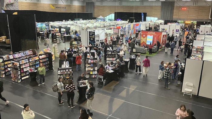 Photo en plongée de la grande salle du Salon du livre, avec des kiosques et des gens qui circulent.
