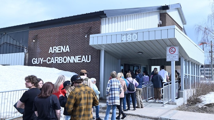 Des personnes forment une file à l'entrée de l'aréna Guy-Carbonneau. 