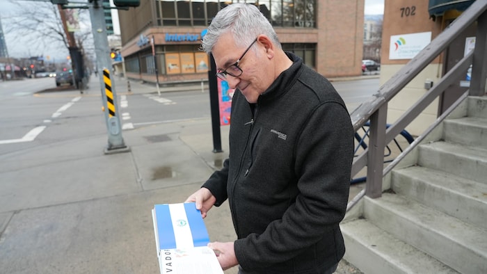 Eduardo Montalvo regarde la page dédiée au Salvador dans le livre qu’il a acheté, alors qu’il se trouve devant le Centre culturel francophone de l’Okanagan, le 30 janvier 2026.