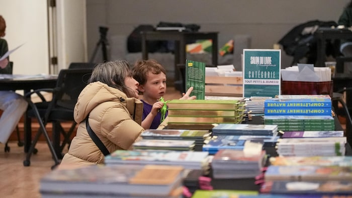 Kellyane Daehn est accroupie à côté de son fils et les deux regardent attentivement un livre au Centre culturel francophone de l’Okanagan, le 30 janvier 2026.