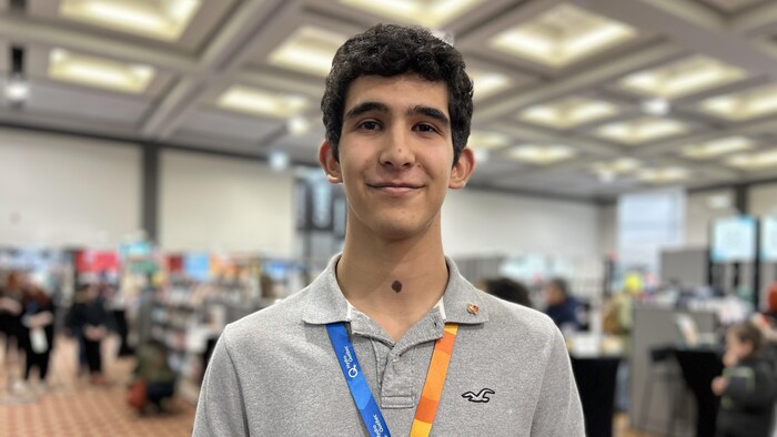 Un grand jeune homme regarde la cam&eacute;ra en souriant