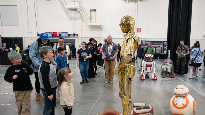 Des enfants sont debout devant un des personnages de « La guerre des étoiles ».