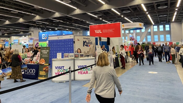 Des personnes dans un hall avec des stands d'exposition.