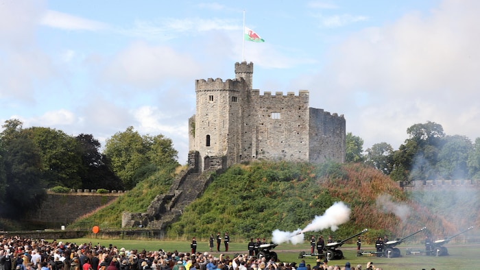 Des personnes regardent une salve d'armes à feu devant le château de Cardiff, en Grande-Bretagne. 
