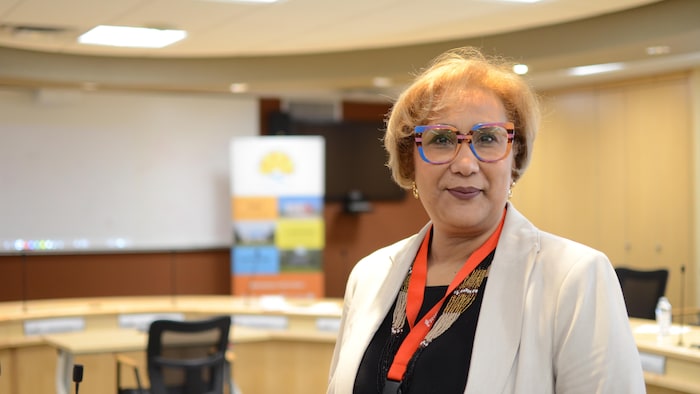 Salwa Meddri dans une salle de réunion où on voit un tableau et des meubles.