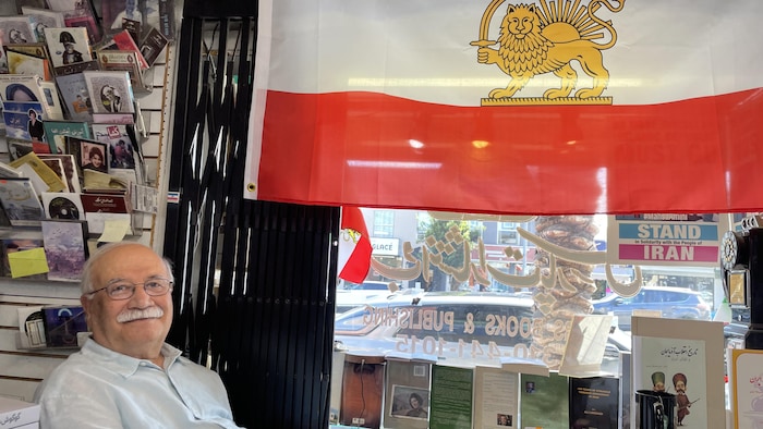 Un homme assis sous un drapeau.