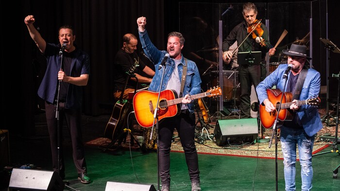 Trois artistes donnent une performance sur scène.