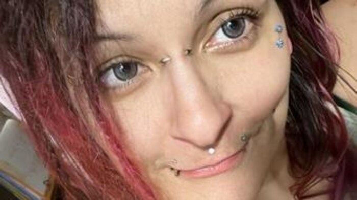 portrait d'une femme avec des perçages dans le visage et les cheveux rouges