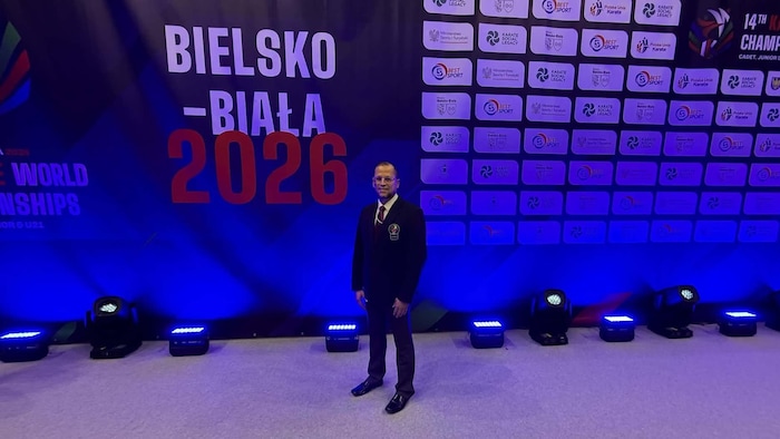Samir Baccouche devant une affiche des Championnats du monde en karaté en Pologne.