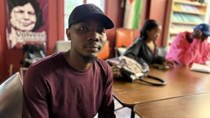 Samuel Bisimwa est assis à une grande table.