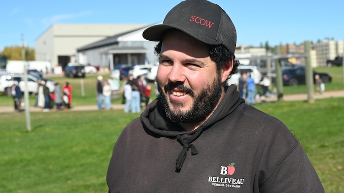 Samuel Bourgeois sourit à la caméra. Il est debout sur le site du verger à Memramcook. 
