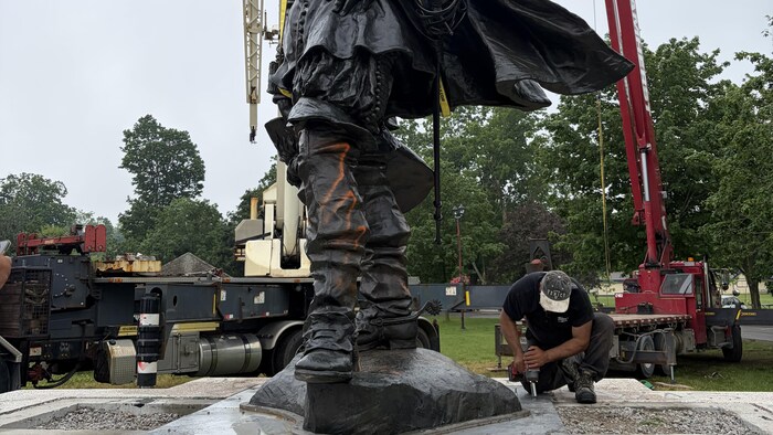 Une statue vandalisée de Samuel de Champlain retirée d'un socle dans un parc.