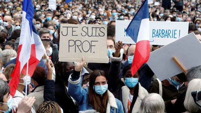 Des manifestants, dont une tient une pancarte sur laquelle on peut lire « Je suis prof ».