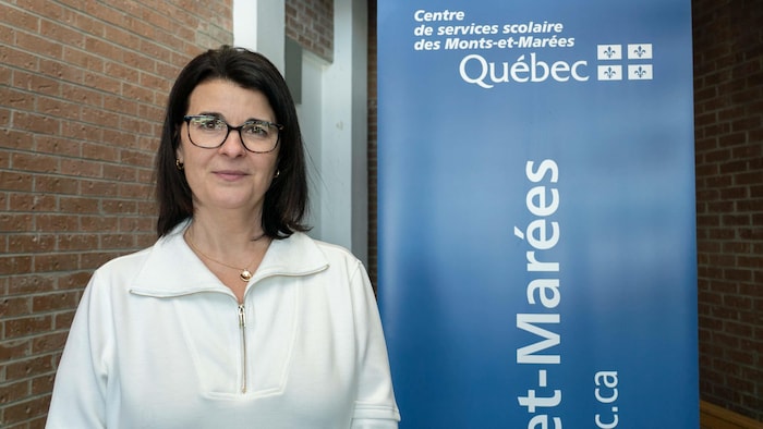 Sandra Théberge devant une affiche du Centre de services scolaire des Monts-et-Marées.