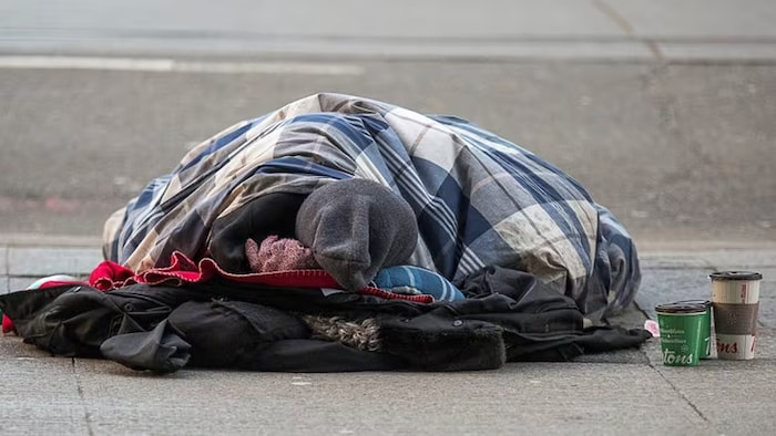 Une personne dort sur un trottoir à Toronto.