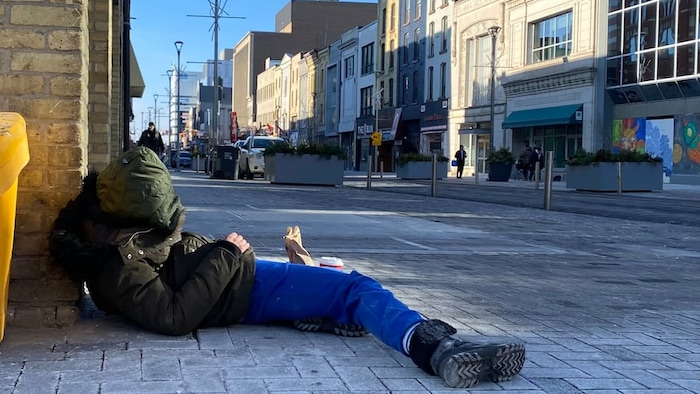 Une personne qui dort sur le bord de la rue.